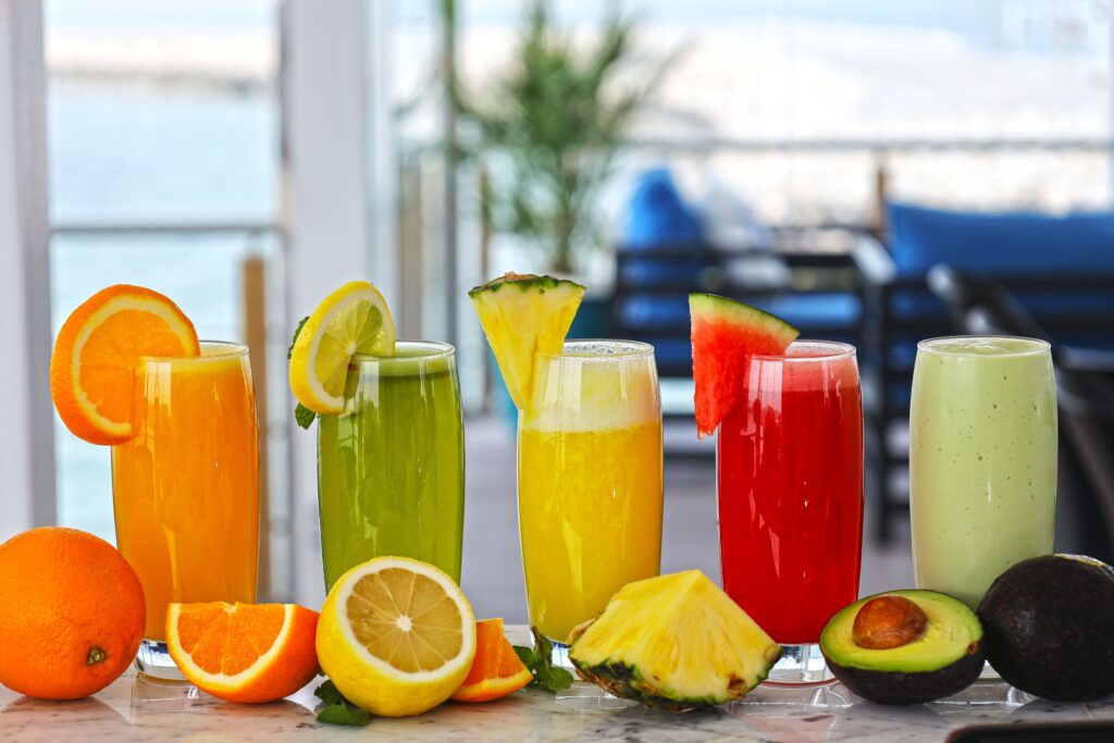 A vibrant display of fresh fruit juices in the sunlight with various garnishes.